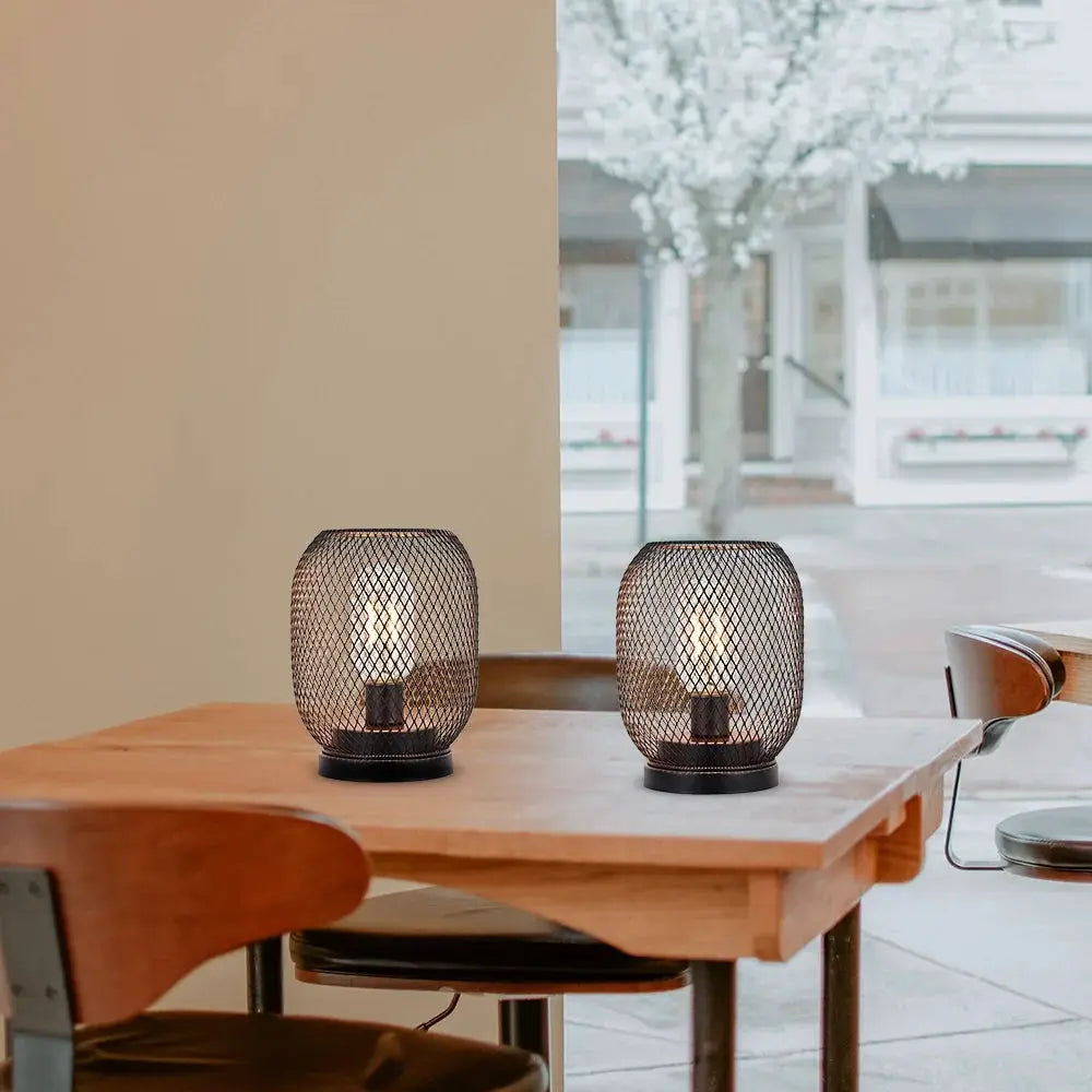 Set of 2 tall battery-powered outdoor table lamps with black mesh metal cages on a wooden table.