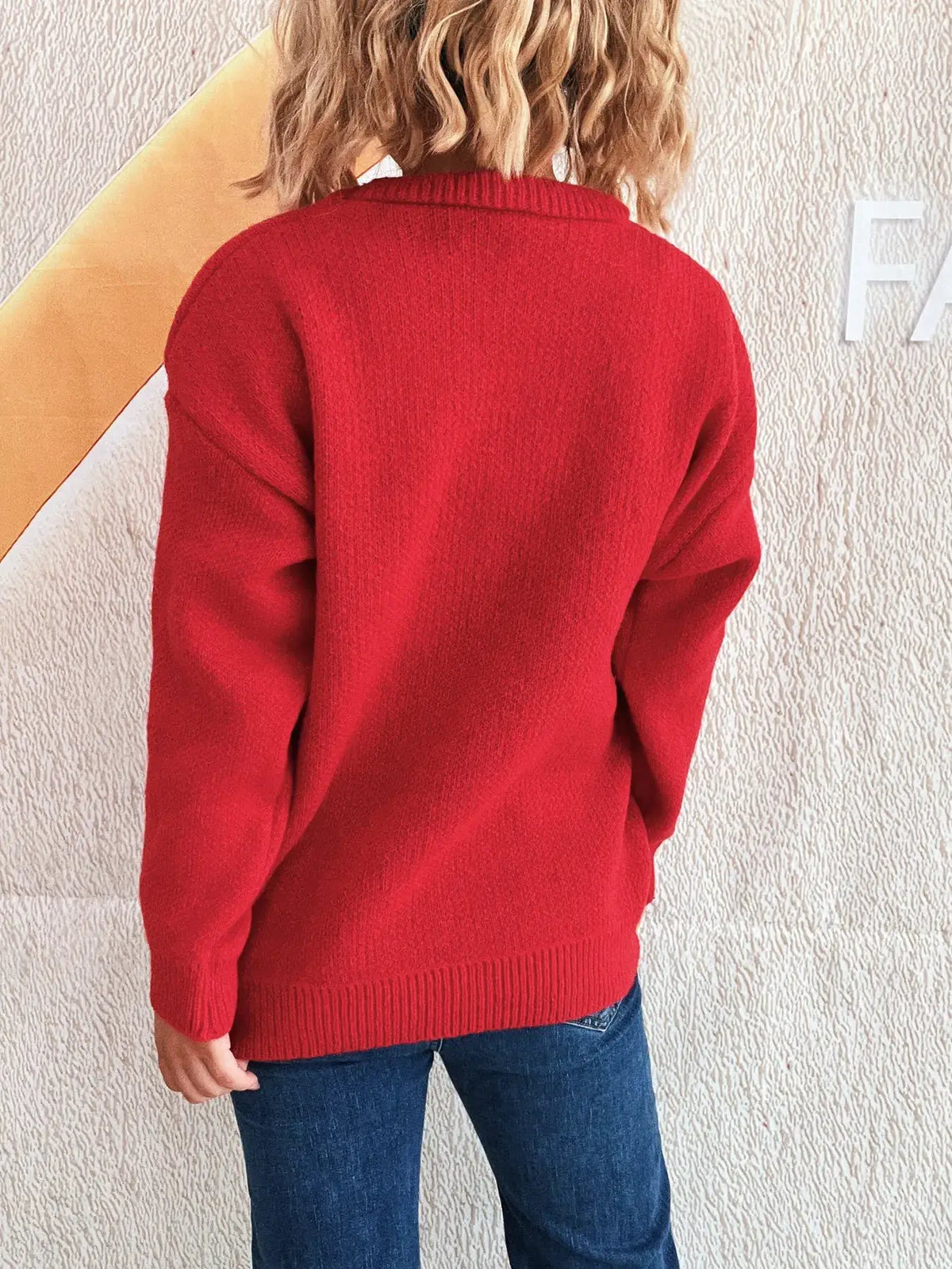 Back view of a woman wearing a red knit round-neck sweater; ribbed hem and cuffs.