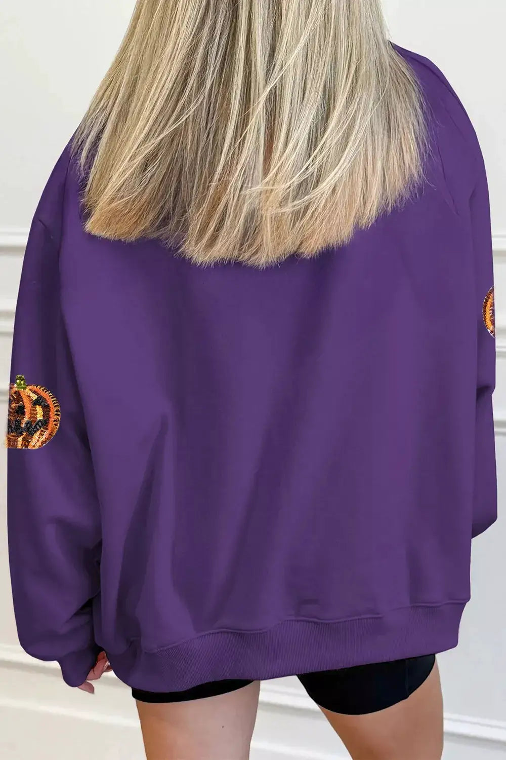Sequin pumpkin Halloween sweatshirt in purple with pumpkin sequin patches on sleeves.