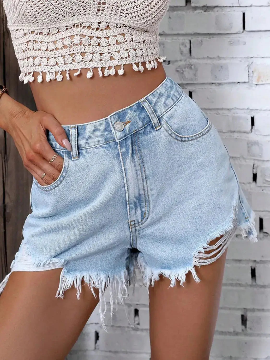 Denim shorts with a light wash and frayed raw hem, button closure.