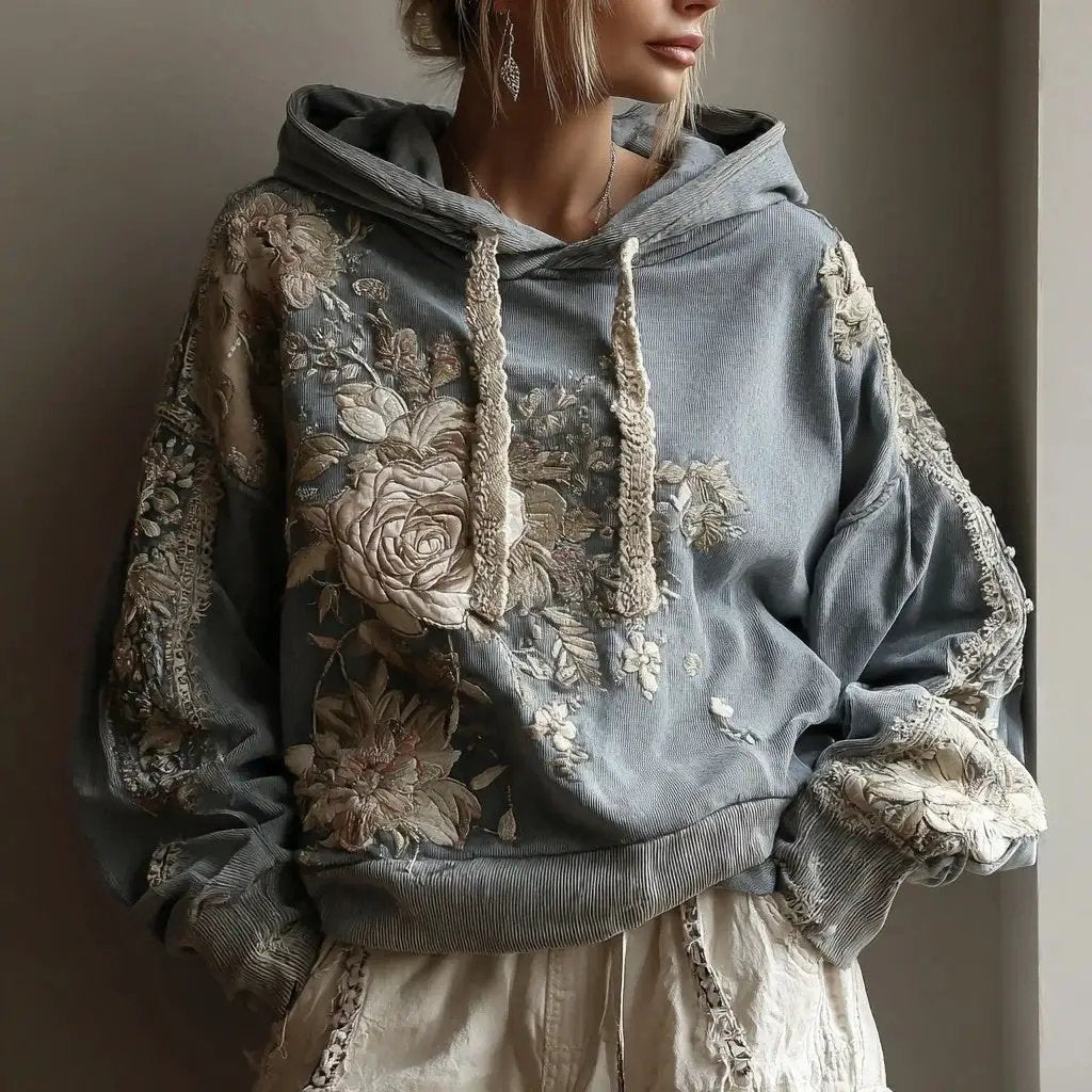 Womens plus-size relaxed-fit pullover hoodie sweatshirt with blue-gray fabric and beige floral embroidery.