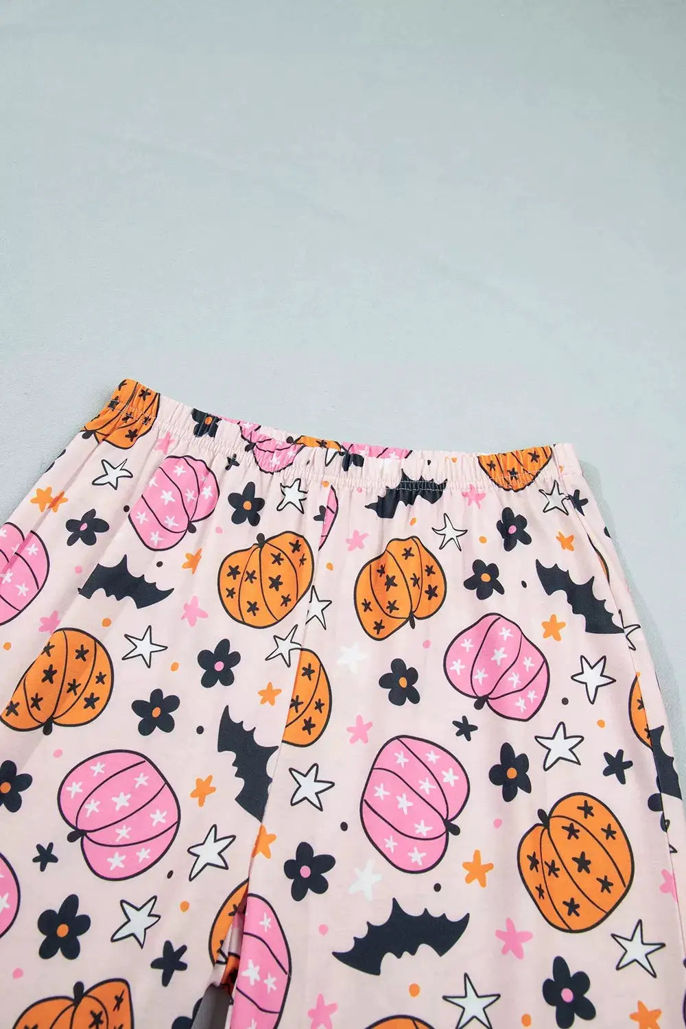 Lounge pants with pink Halloween pumpkin print, featuring orange pumpkins, bats and stars, elastic waistband.