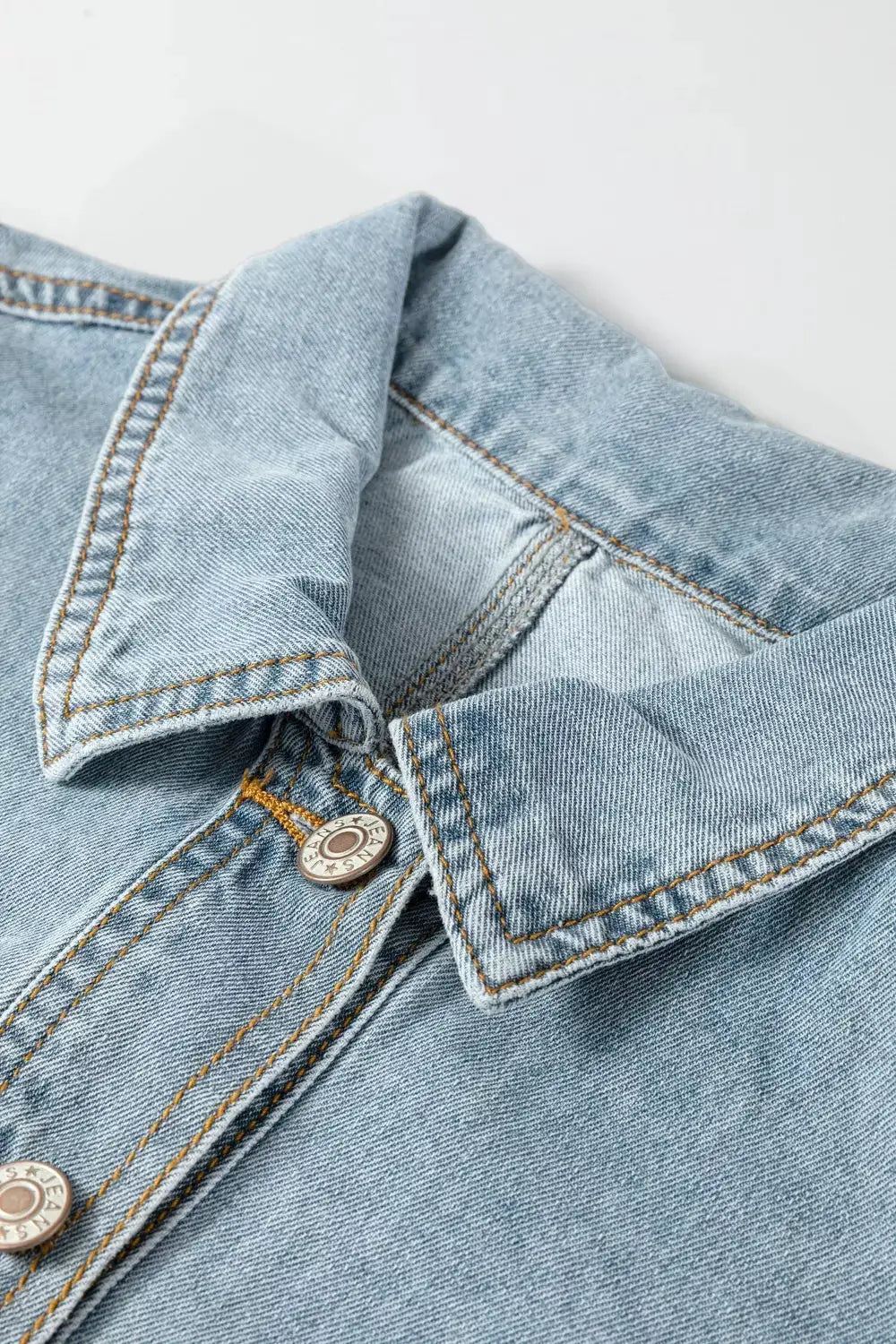 Classic light-wash denim jacket close-up of collar with metal buttons