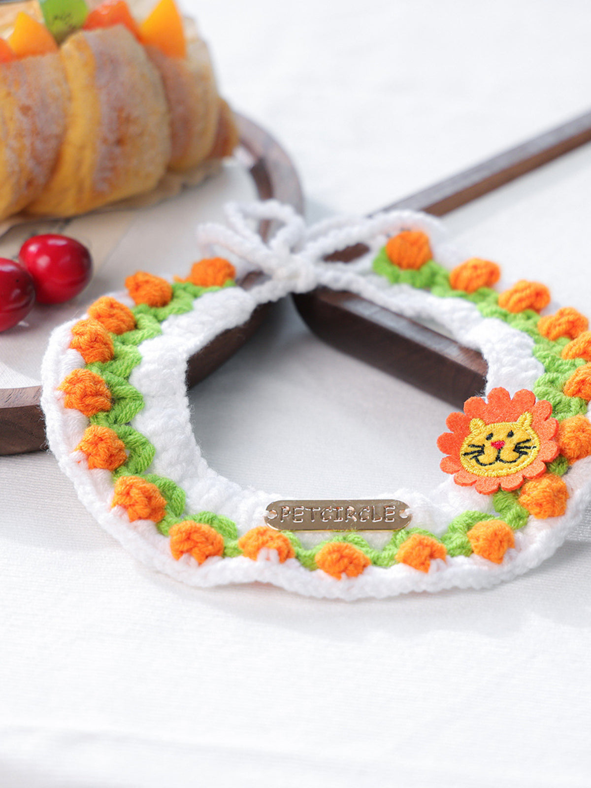 Contrast Pet Scarf crocheted with white trim, orange pom-poms and a sunflower motif, PetGirl tag