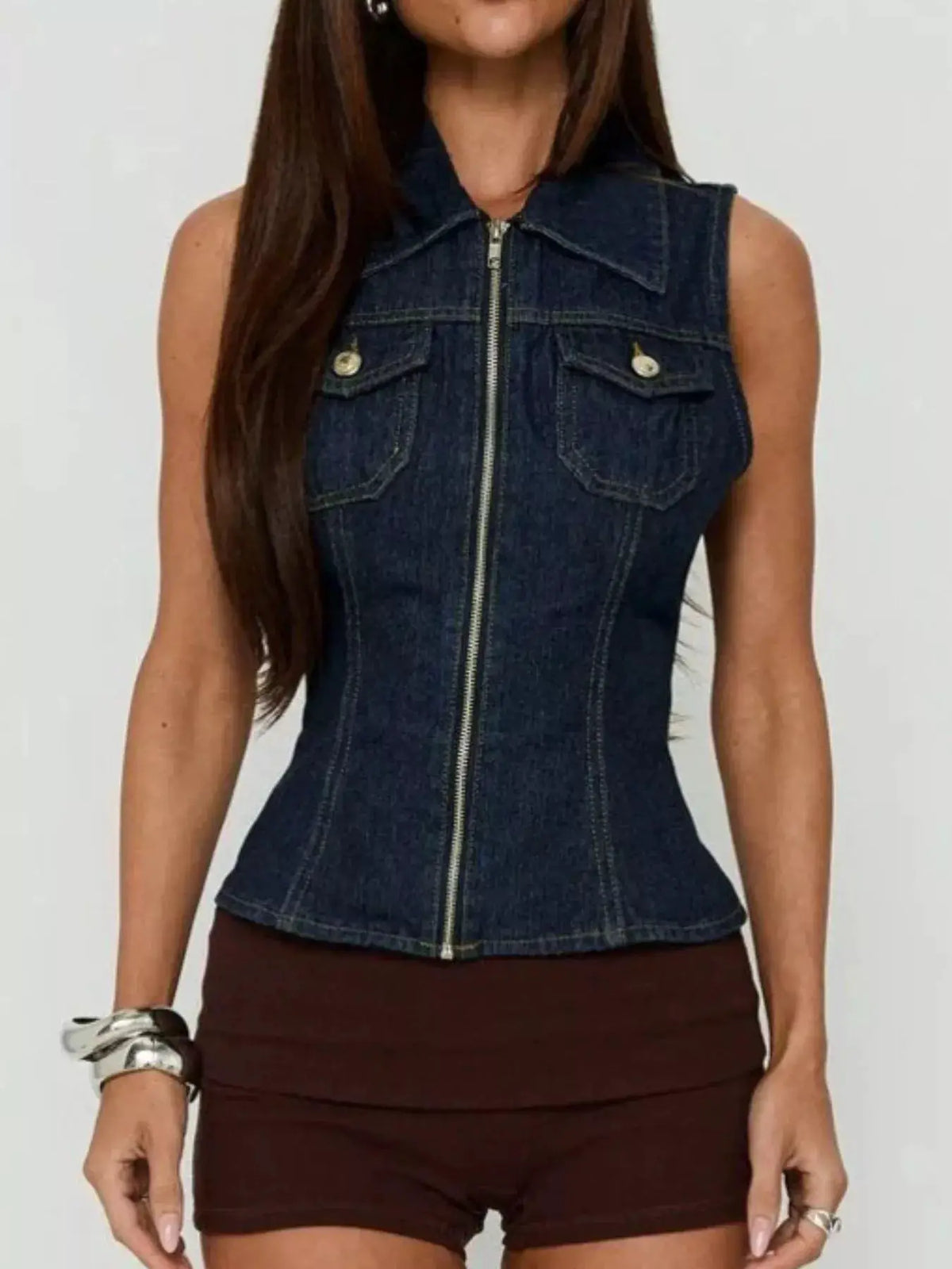 Sleeveless zip-up denim vest in dark blue with front pockets and flap details.