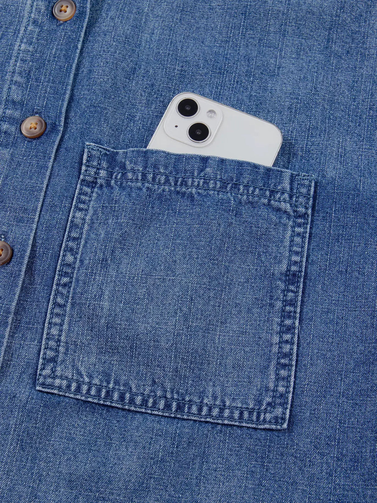 Relaxed denim shirt with chest pocket holding a smartphone, blue denim fabric