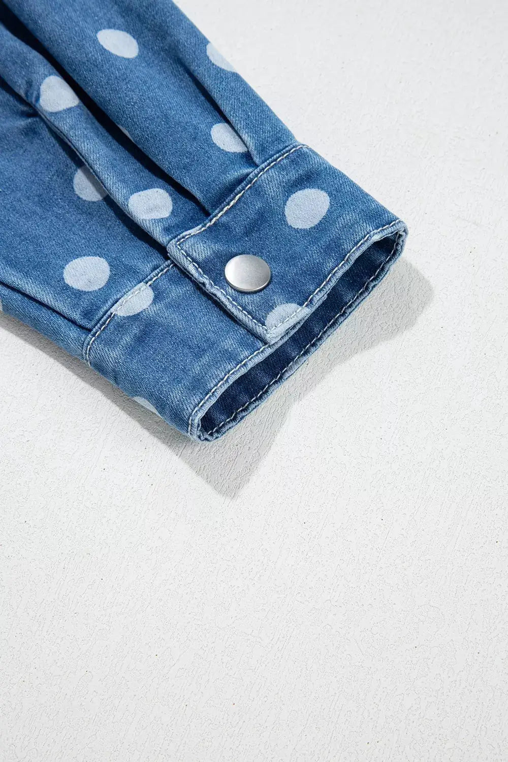 Polka dot long-sleeve denim tunic jacket in blue with button closure.