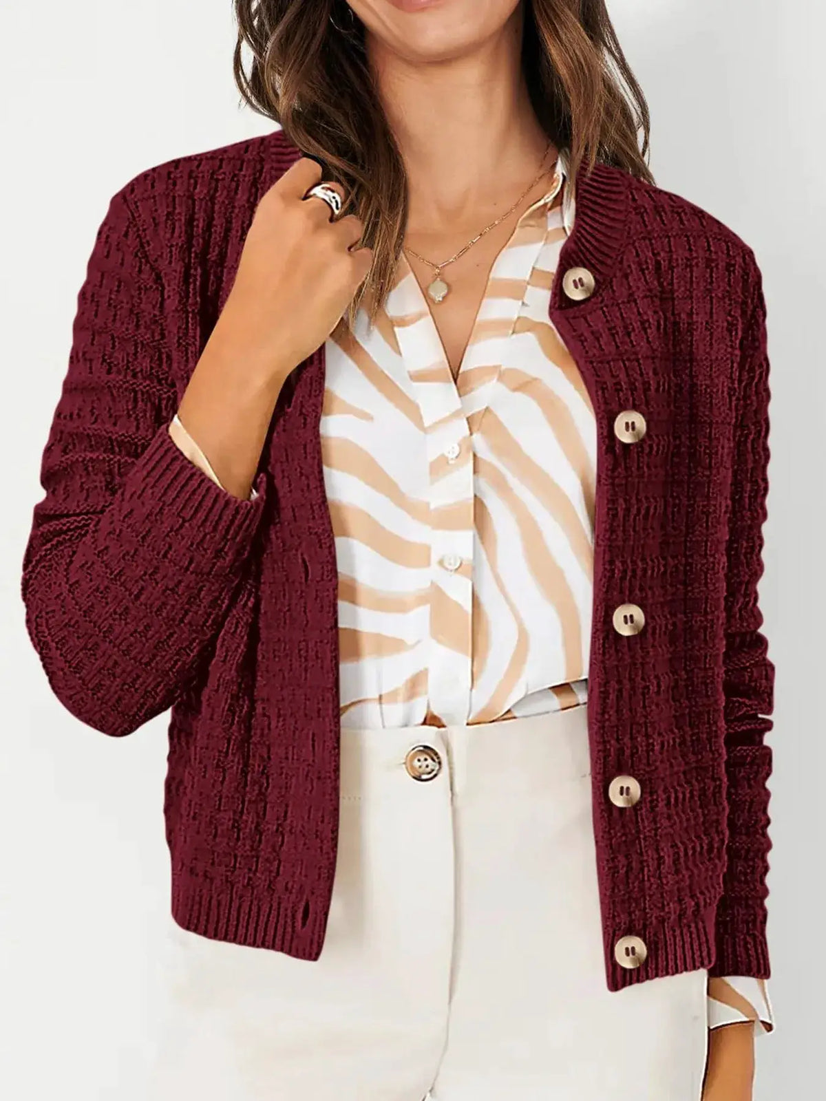 Textured stretchy knit button-front cardigan in burgundy, worn over a beige-and-white striped blouse