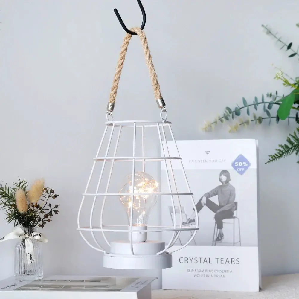 Cordless white accent lamp in a metal wire cage with an Edison-style bulb hanging from a rope.