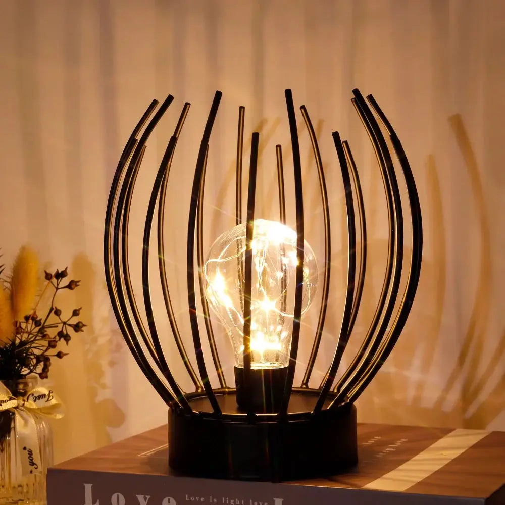 7 inches tall battery-powered table lamp by JHY DESIGN with a black curved-metal spoke frame and warm bulb.