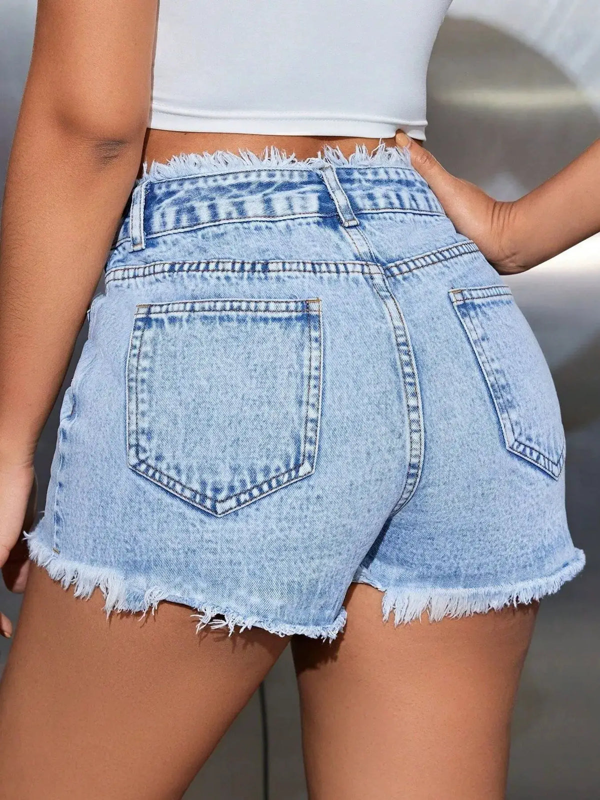 High-waisted washed denim shorts with frayed hem and stretch fabric in light blue.