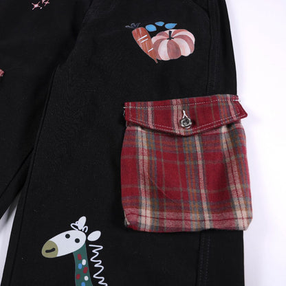 Black denim jacket with a red plaid pocket flap and cartoon patches (pumpkin and giraffe)