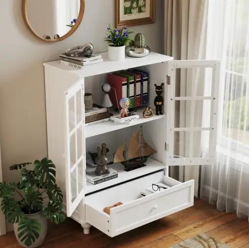 Minimalist white buffet cabinet with double glass doors and a bottom drawer in a bright living room.