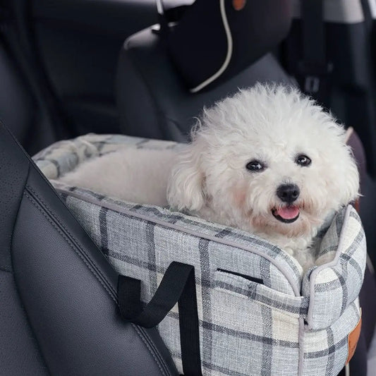 Car pet travel bag in gray plaid with black straps, fluffy white dog inside.