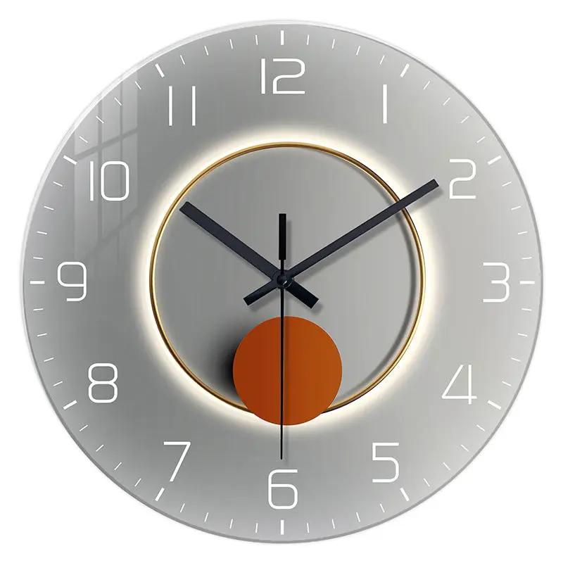 Wall-mounted decorative clock with silver metallic face, glowing inner ring, and orange disk pendulum