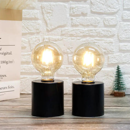 7-inch tall black battery-powered table lamps set of 2 with clear glass bulbs on black cylindrical bases