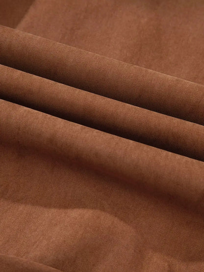 Dress fabric close-up in warm brown with soft folds and smooth texture
