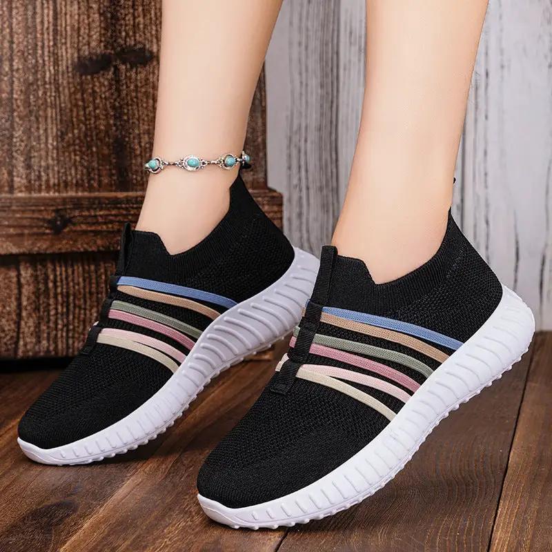 Women's breathable mesh slip-on sneakers with black knit upper and multicolor stripe bands, white flexible sole.