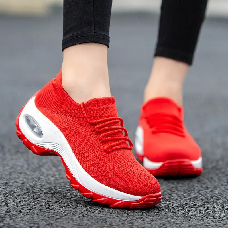 Pair of red knit women's athletic sneakers with white sole and visible air unit.
