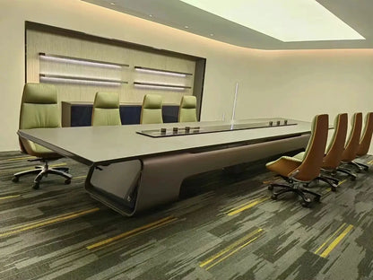 Large executive conference table with built-in power panel in a modern boardroom, flanked by tan leather chairs.