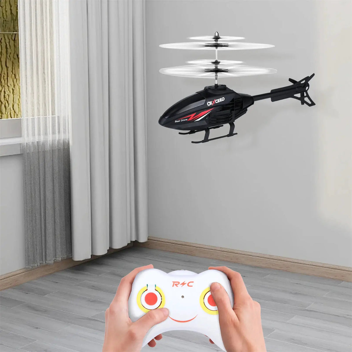 RC helicopter toy, black with red graphics, flying indoors with a white controller in the foreground.