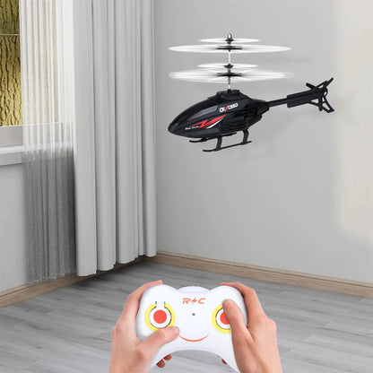 RC helicopter toy, black with red graphics, flying indoors with a white controller in the foreground.