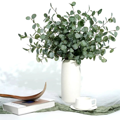 Artificial eucalyptus stems in a white textured vase with grey-green leaves