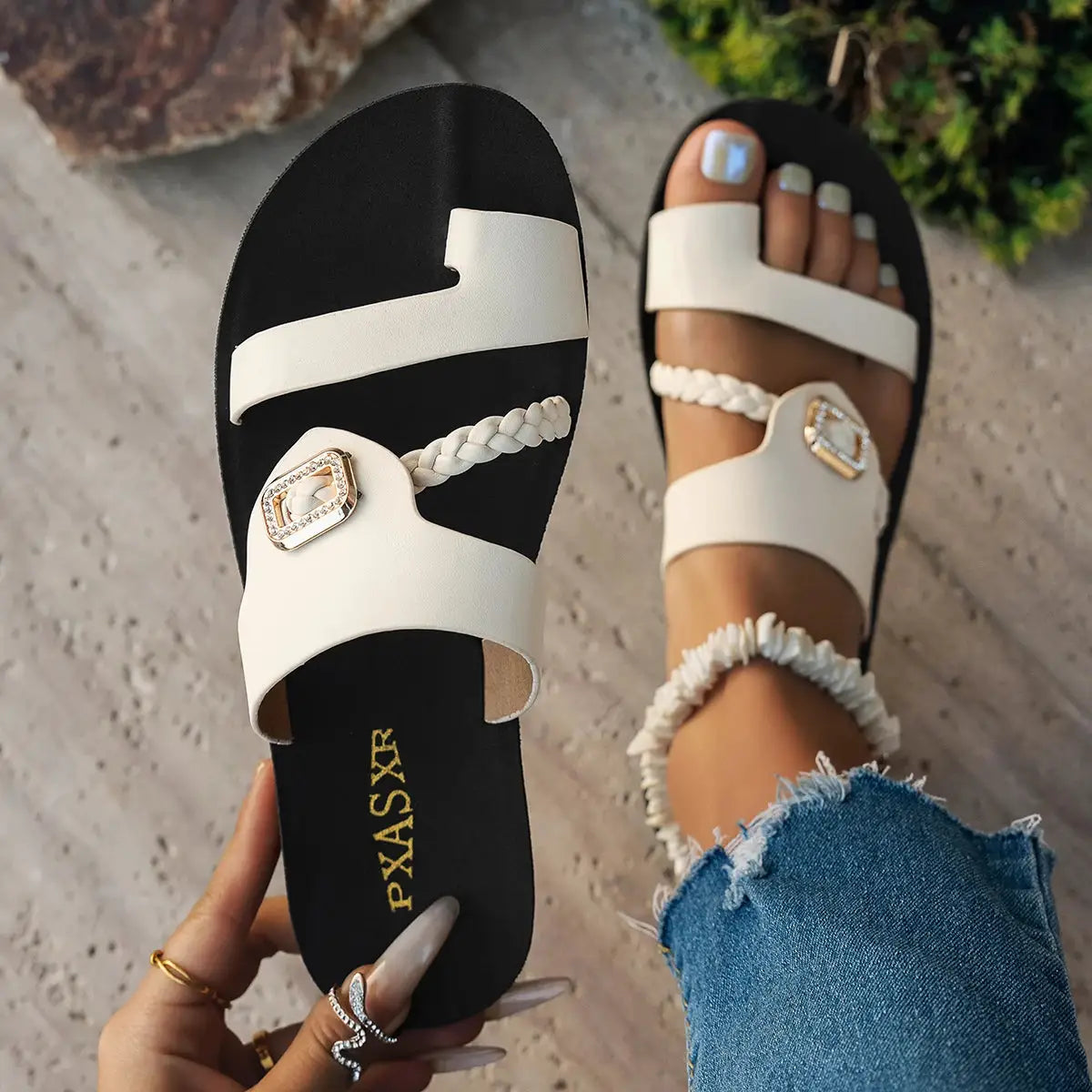Pair of women's white flat sandals with braided strap and diamond-buckle accents