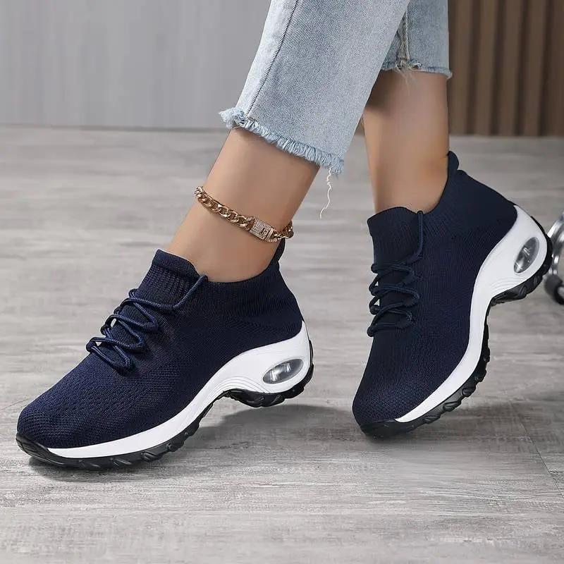 Women’s navy knit sneakers with white sole and visible air-cushioned midsole.