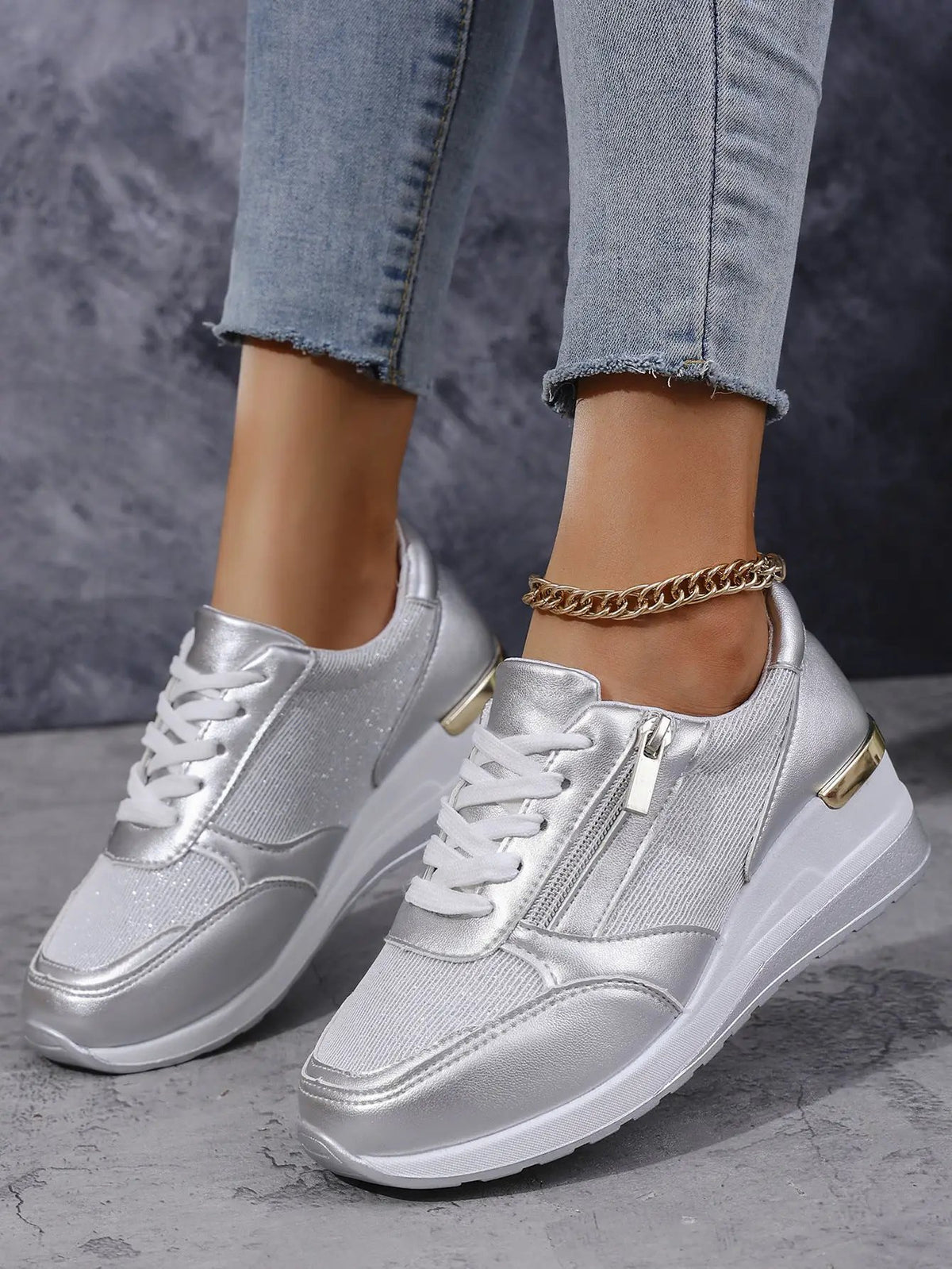 Pair of women's silver metallic sneakers with lace-up front, side zipper, and chunky white sole.