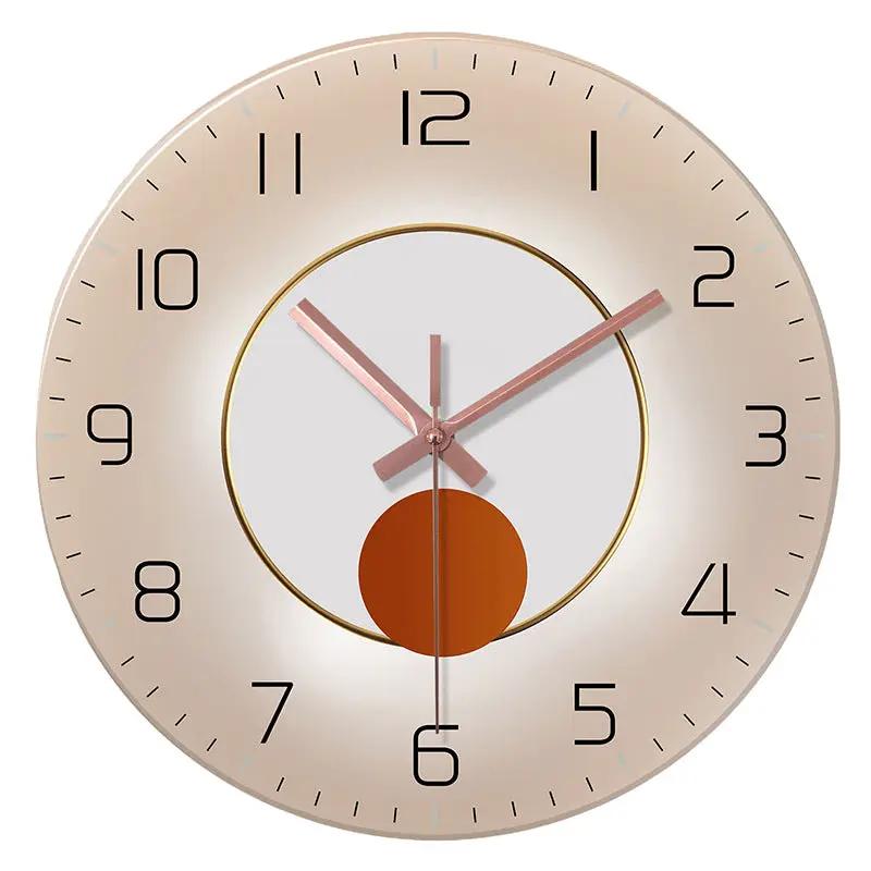 Wall-mounted decorative clock with rose-gold hands, beige-gold bezel, and central orange disk.