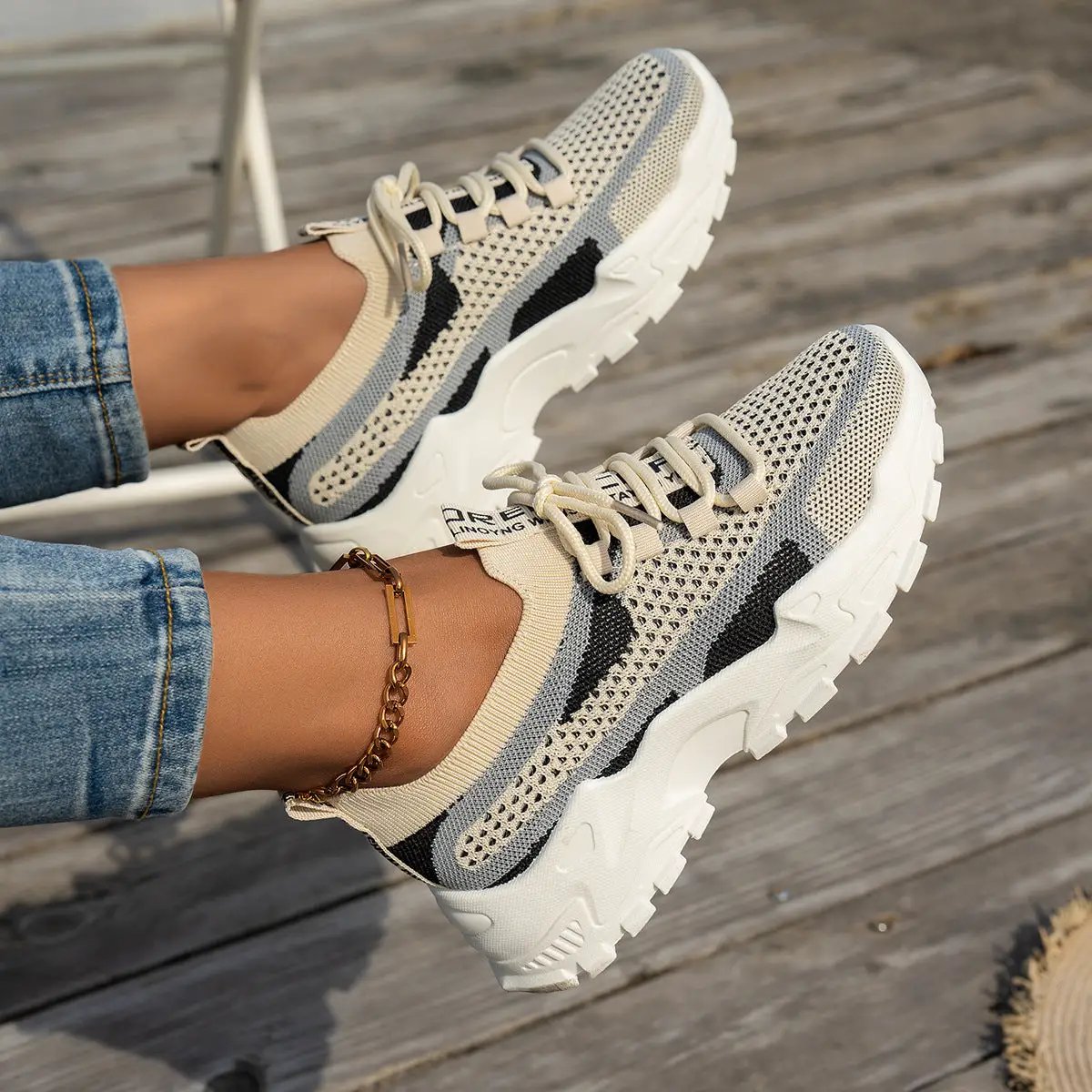 Pair of women's Flyknit mesh sneakers in beige with black accents, lace-up, chunky white sole.