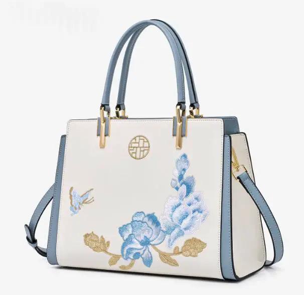 AdTec handbag tote in cream with blue handles and blue floral embroidery.