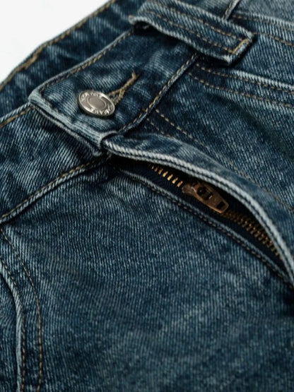 Men's Relaxed Wide Leg Denim Shorts in blue washed cotton; close-up of metal button and zipper on denim fabric.