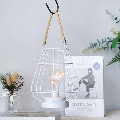 Cordless white accent lamp in a metal wire cage with an Edison-style bulb hanging from a rope.