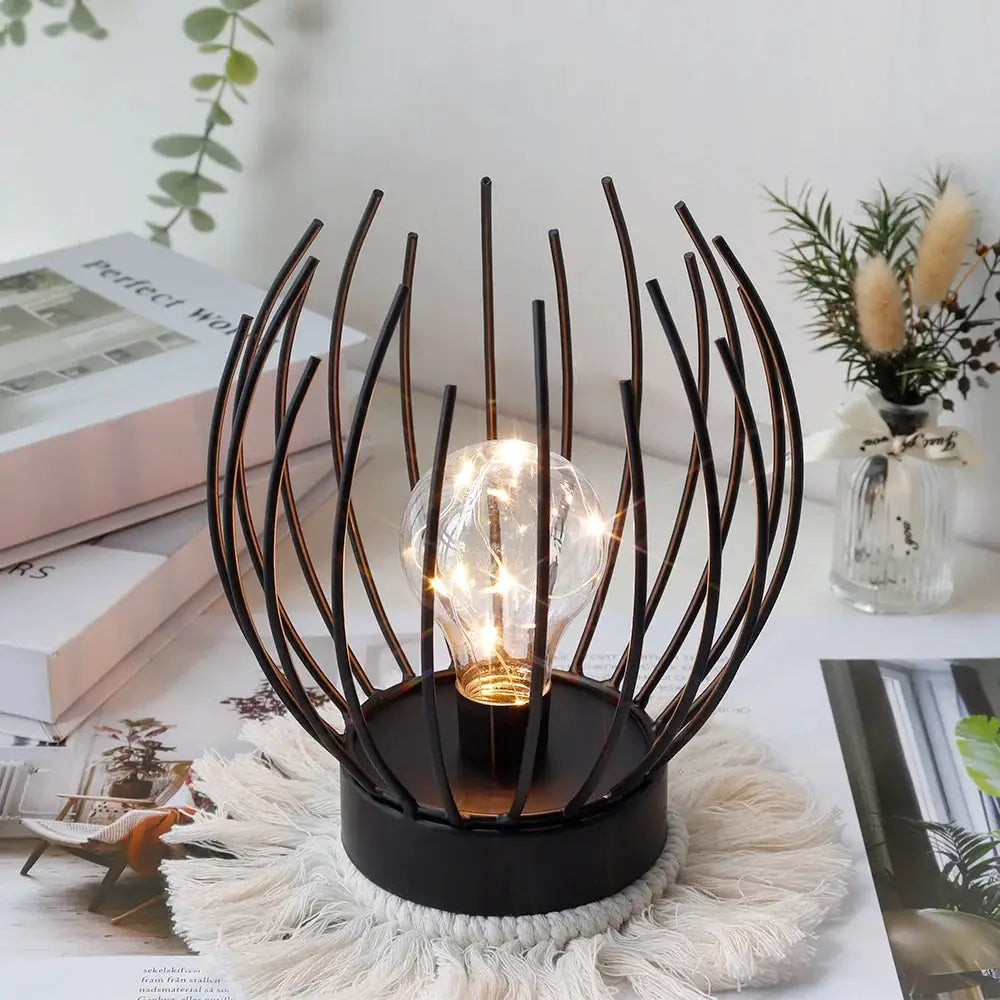 7-inch tall battery-powered table lamp with a black metal orb frame around a glowing filament bulb